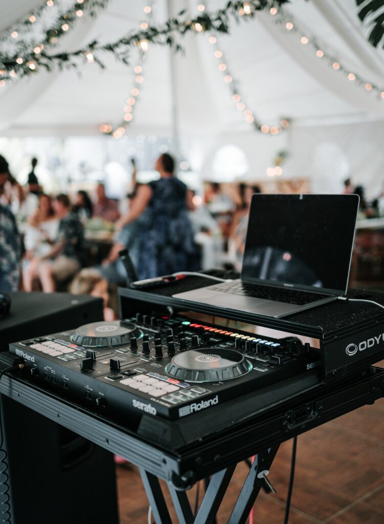 table de mixage d'un DJ de mariage avec les invités qui dansent en arrière plan